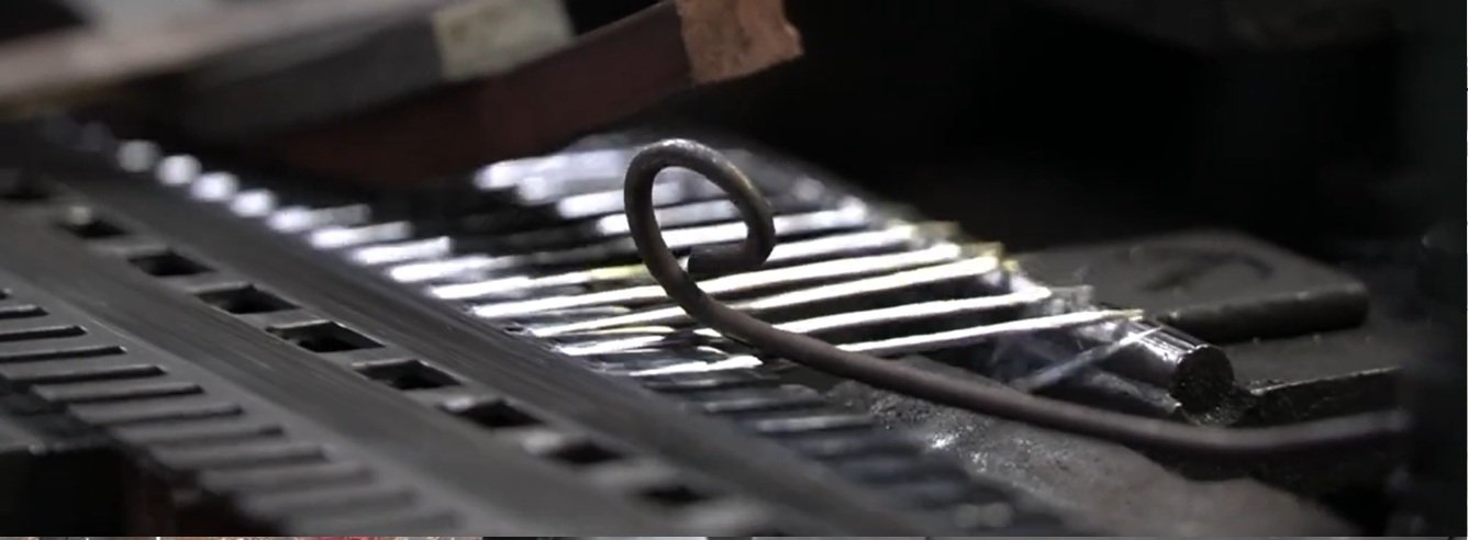 Steel wire being hand-formed on a coiling machine during needle production