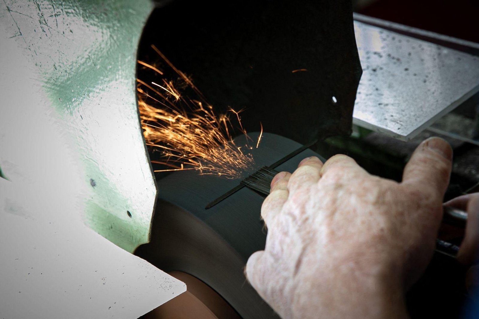 Sparks fly as a needle is ground and sharpened by hand