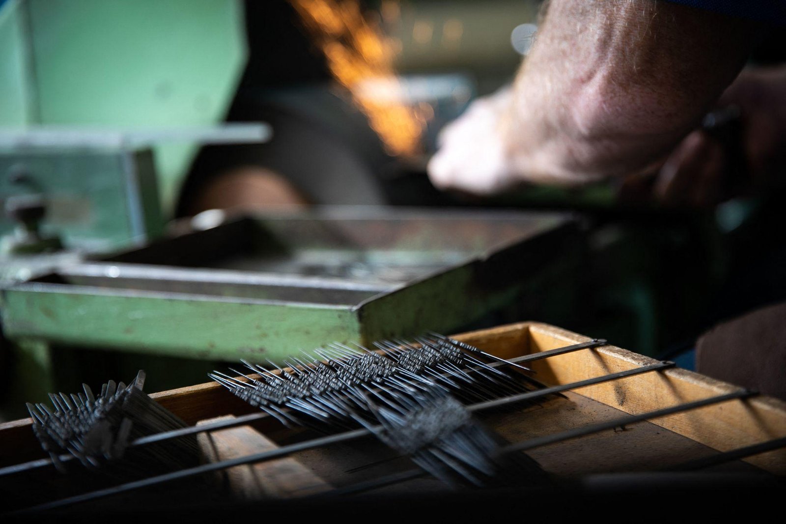 A craftsman sharpening needles by hand on a grinding wheel at the Toshiko workshop