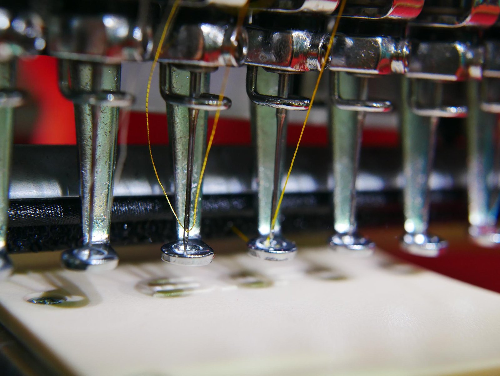 Embroidery needle threaded with gold thread mid-production
